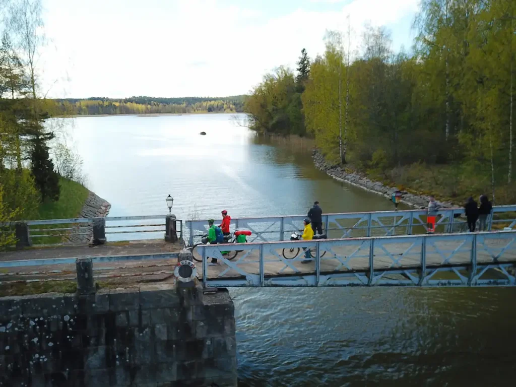 "Pyöräilijöitä ja jalankulkijoita sillalla Kemiönsaaren vesistön yllä keväisessä maisemassa.