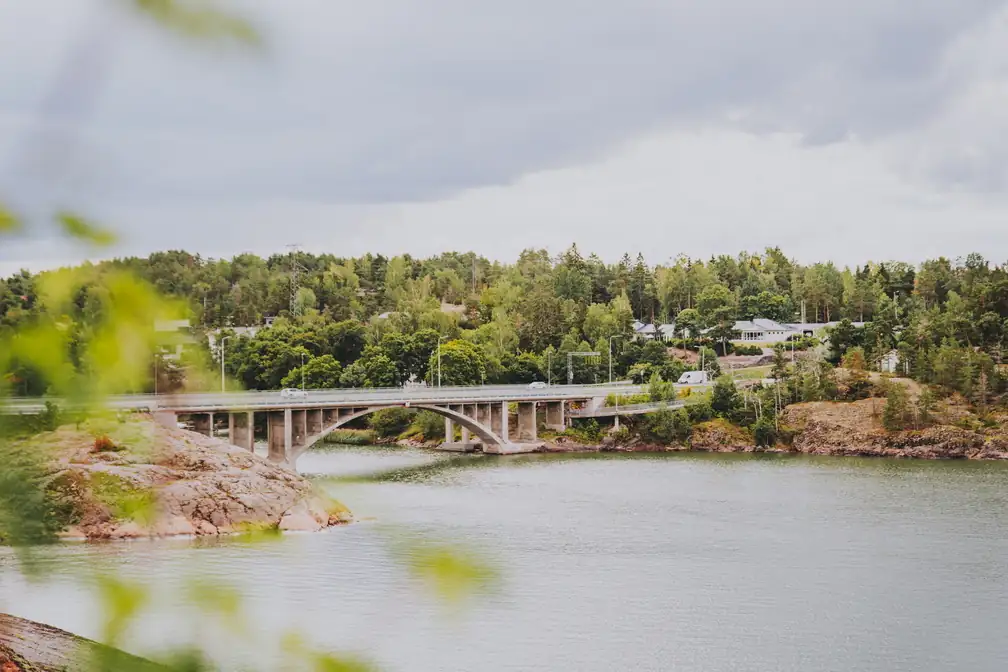Silta saaristomaisemassa, taustalla metsää ja meri edustalla.
